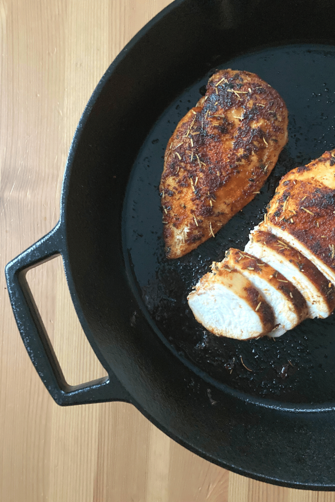 2 Chicken Breasts in a cast iron pan, one is sliced