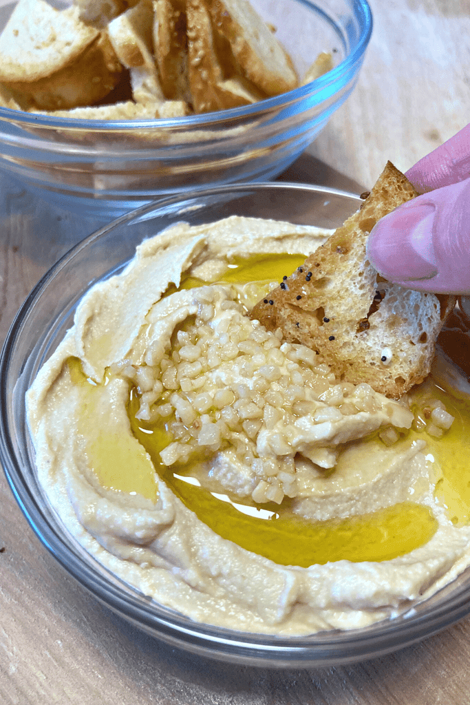 Sourdough bagel chip dipped in garlic hummus