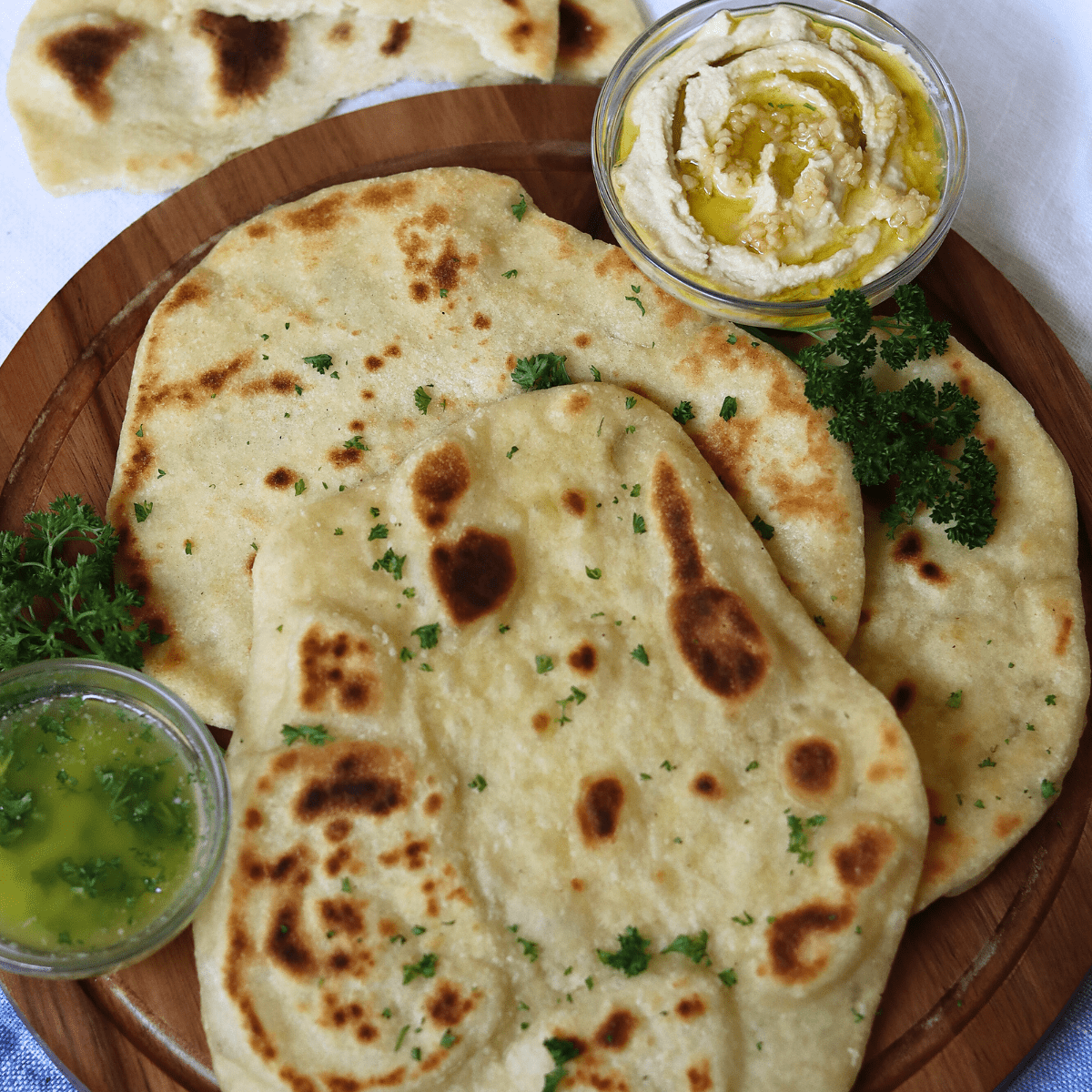 sourdough flatbread on a platter with garlic butter and hummus