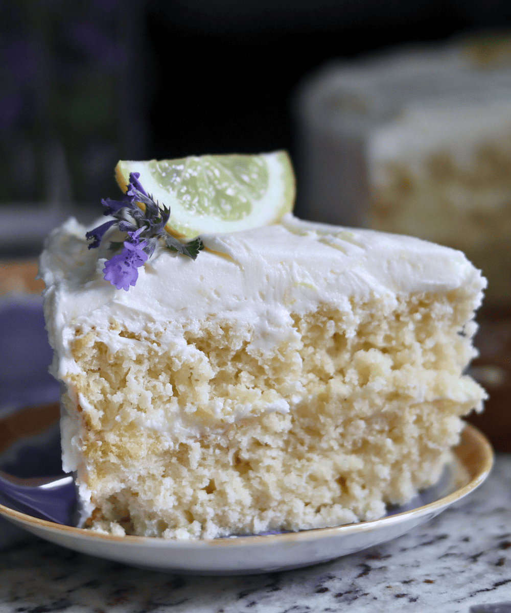slice of sourdough lemon cake topped with cat mint and a wedge of lemon