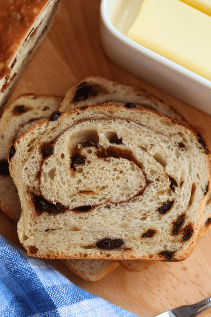 Cinnamon Raisin Swirl Sourdough Bread on a cutting board by butter