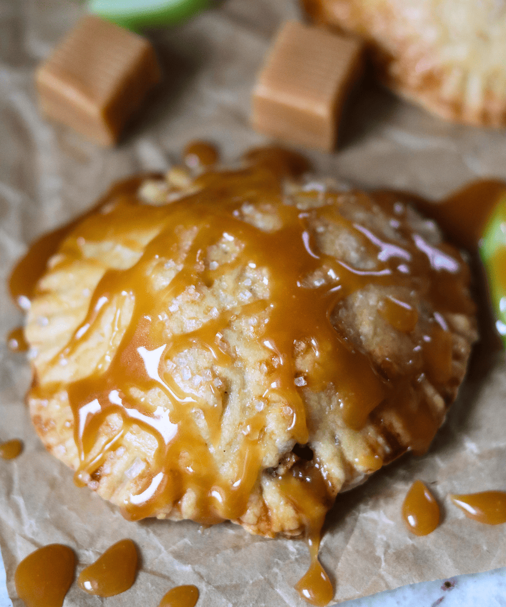 Salted Caramel Apple Sourdough Hand Pies with caramel sauce on parchment paper