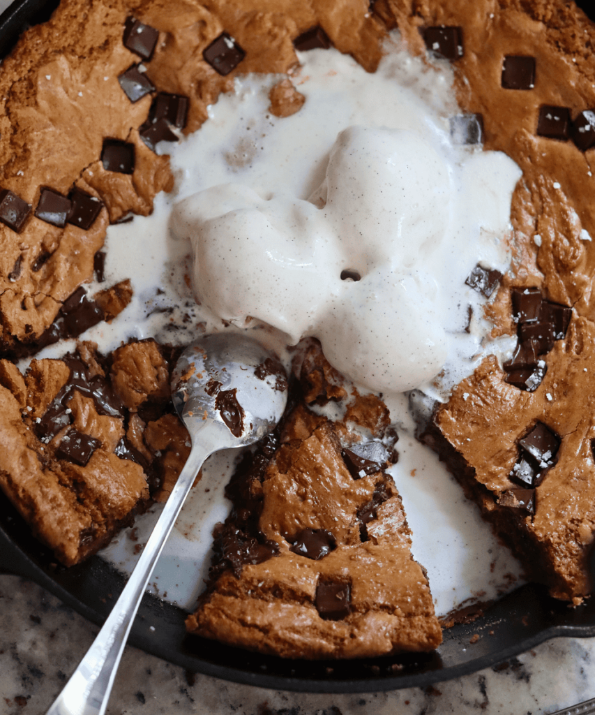 Sourdough Chocolate Chip Skillet Cookie with scoops of vanilla ice crea on top