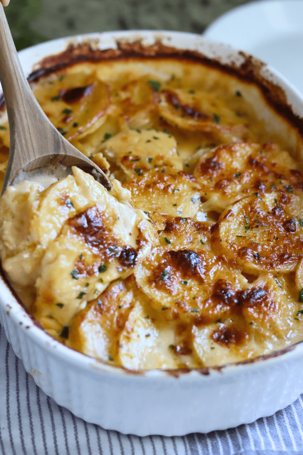 Scooping out Sourdough Au Gratin Potatoes with a wooden spoon