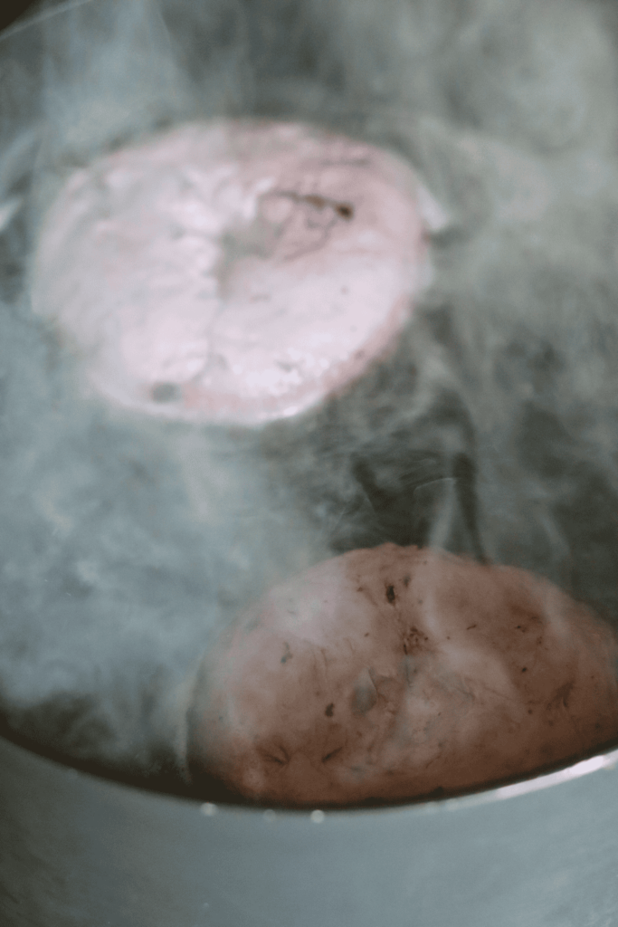 Sourdough Blueberry Bagels boiling in a large pot