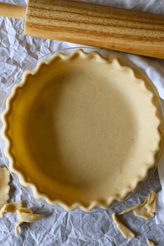 Sourdough Discard Pie Crust in a pie plate with a rolling pin near by