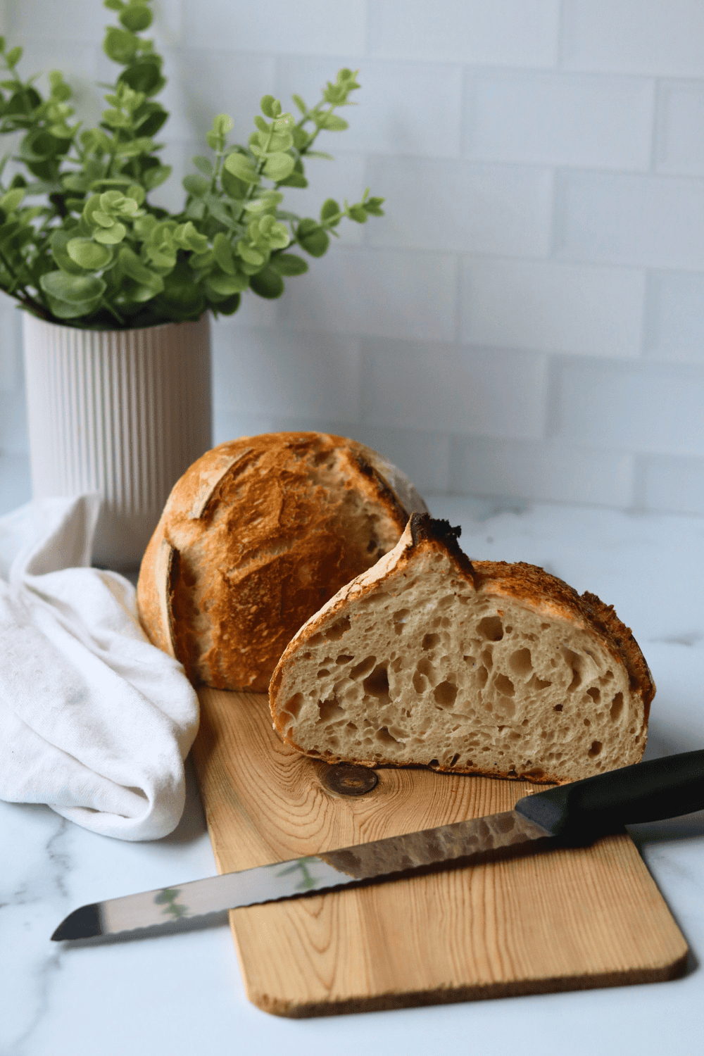 a loaf of sourdough slices in half on a cutting board