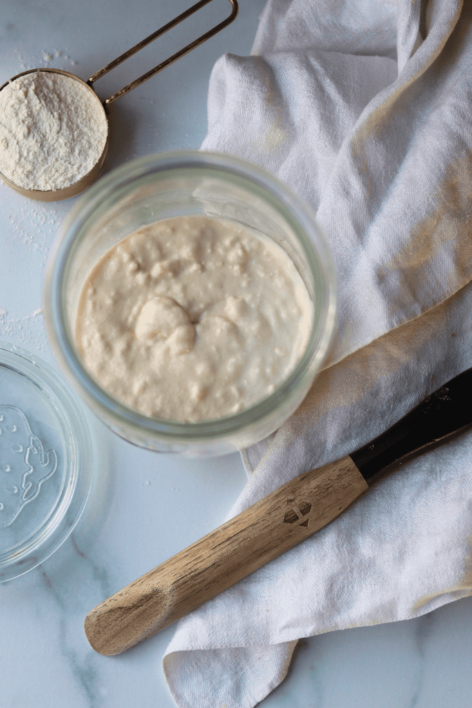feeding a sourdough starter in a glass jar