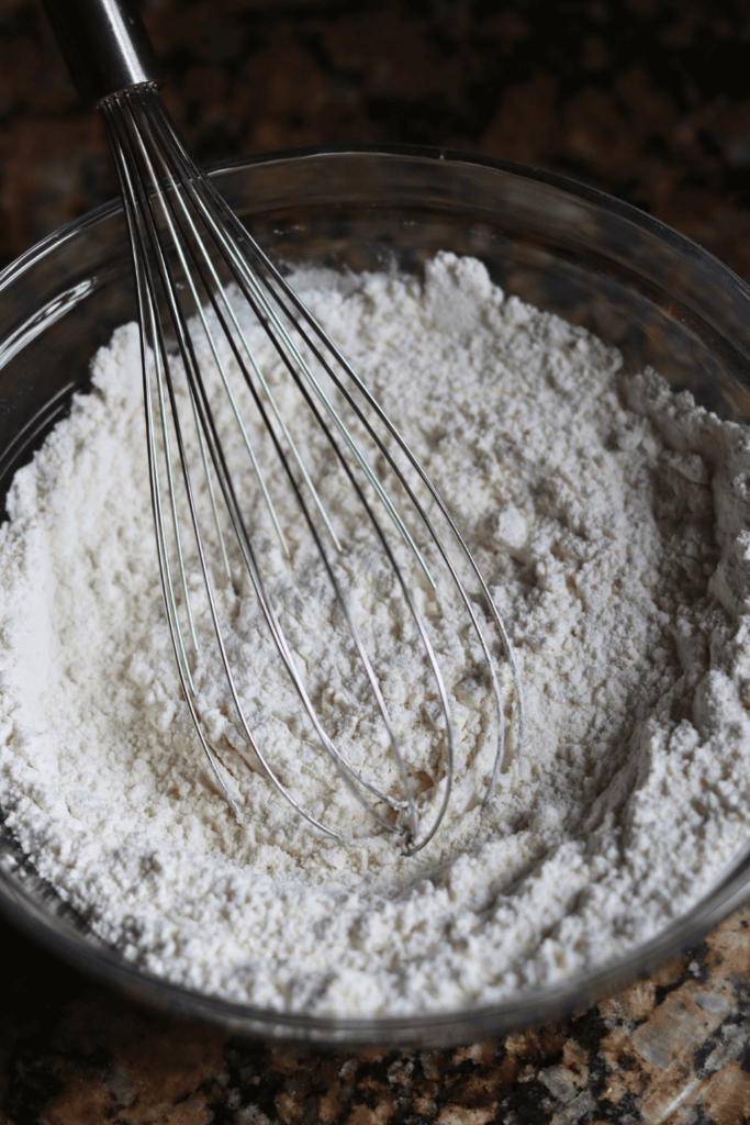 dry ingredients mixed together in a glass bowl with whisk