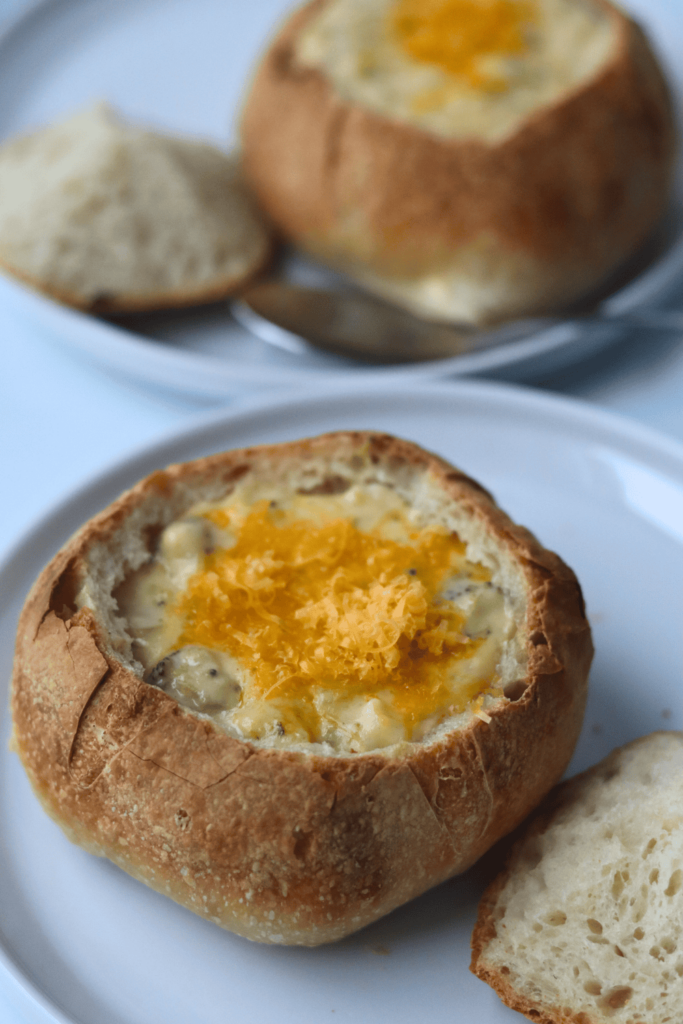 two bread bowls with soup on a plate