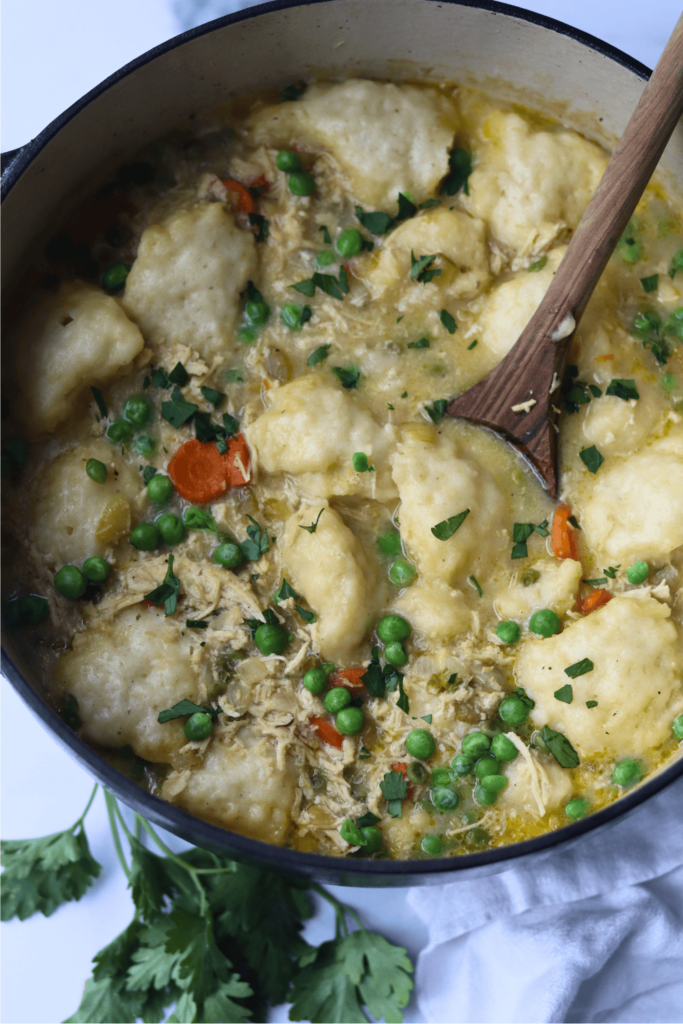 A pot of chicken and dumplings with green peas