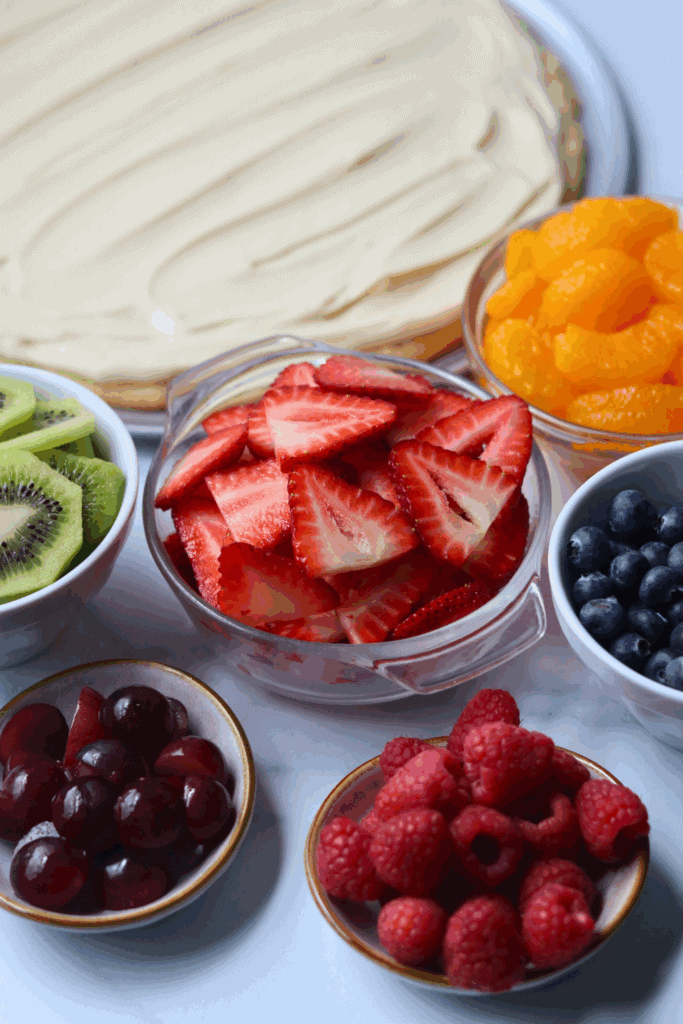 pizza with cream cheese and different slices of fruits in a bowl for making sourdough fruit pizza