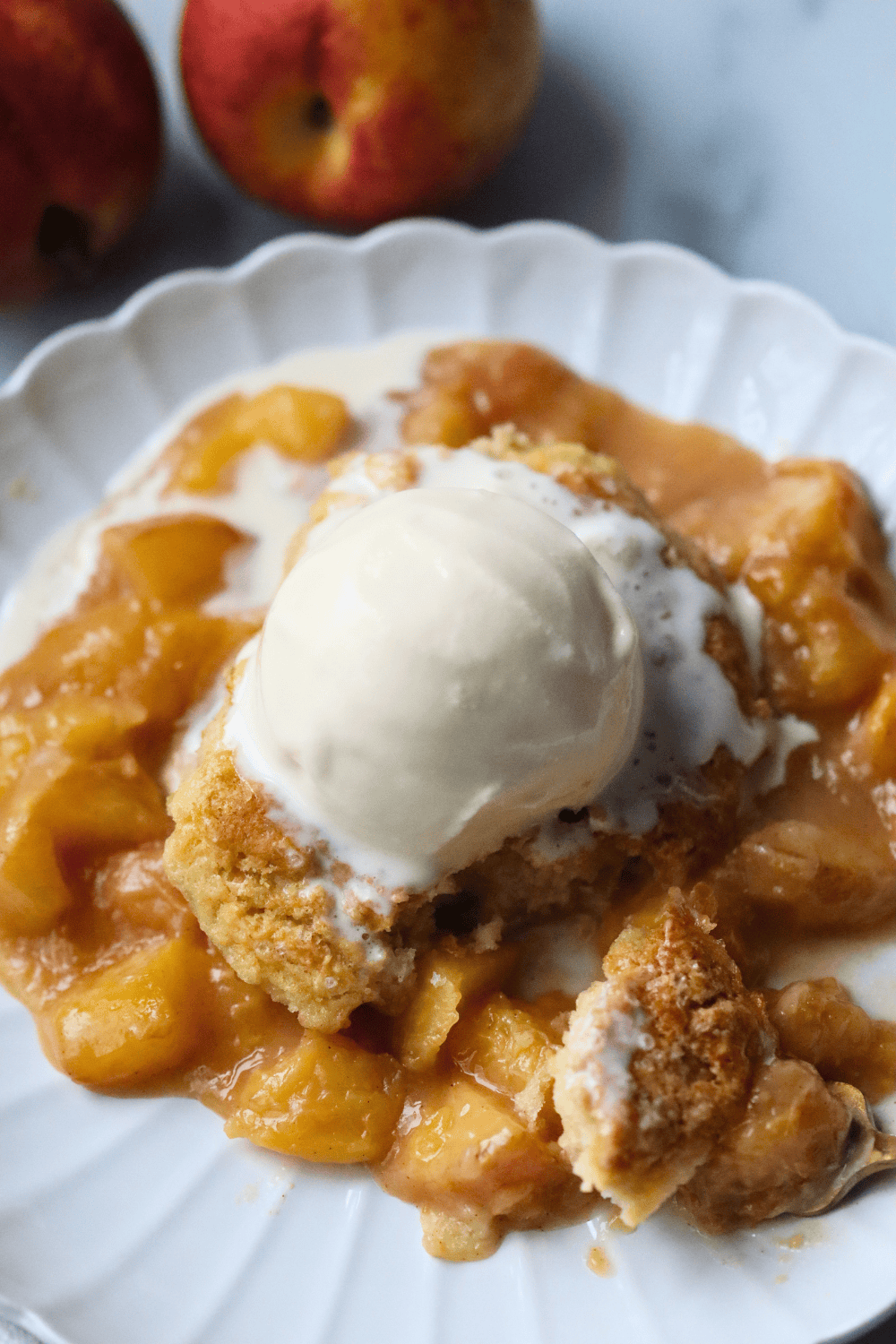 sourdough peach cobbler with a scoop of ice cream on top