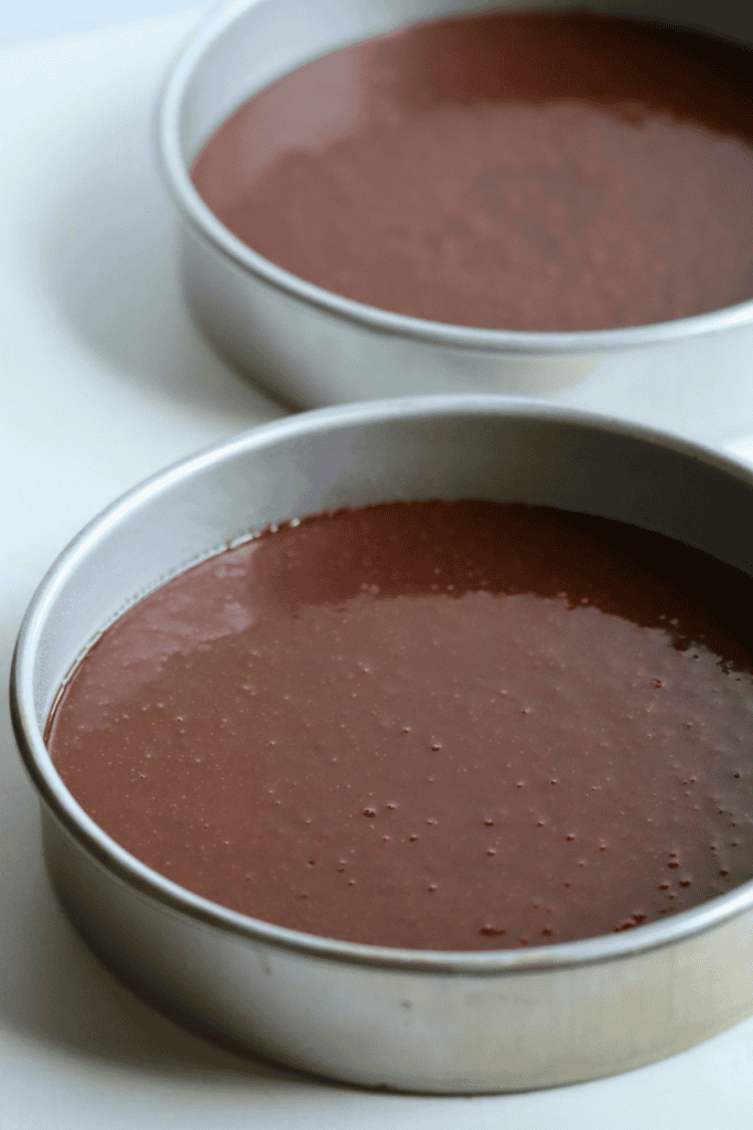 chocolate cake batter poured into the cake pans