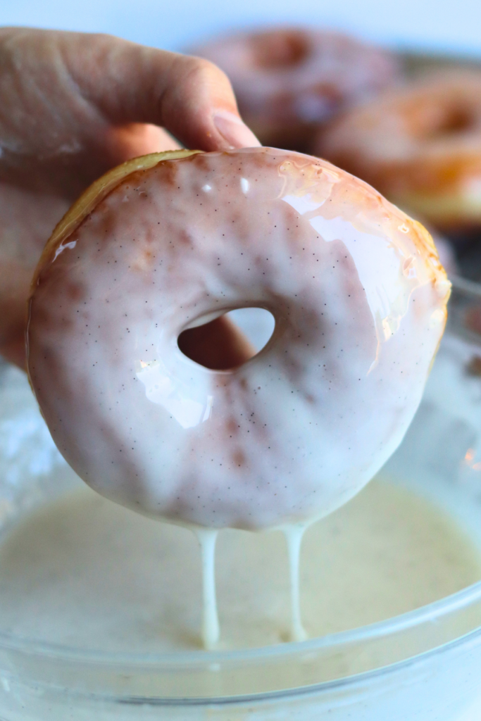 dipping the donut into the glaze