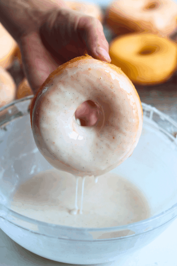 dipping the sourdough donuts into the glaze