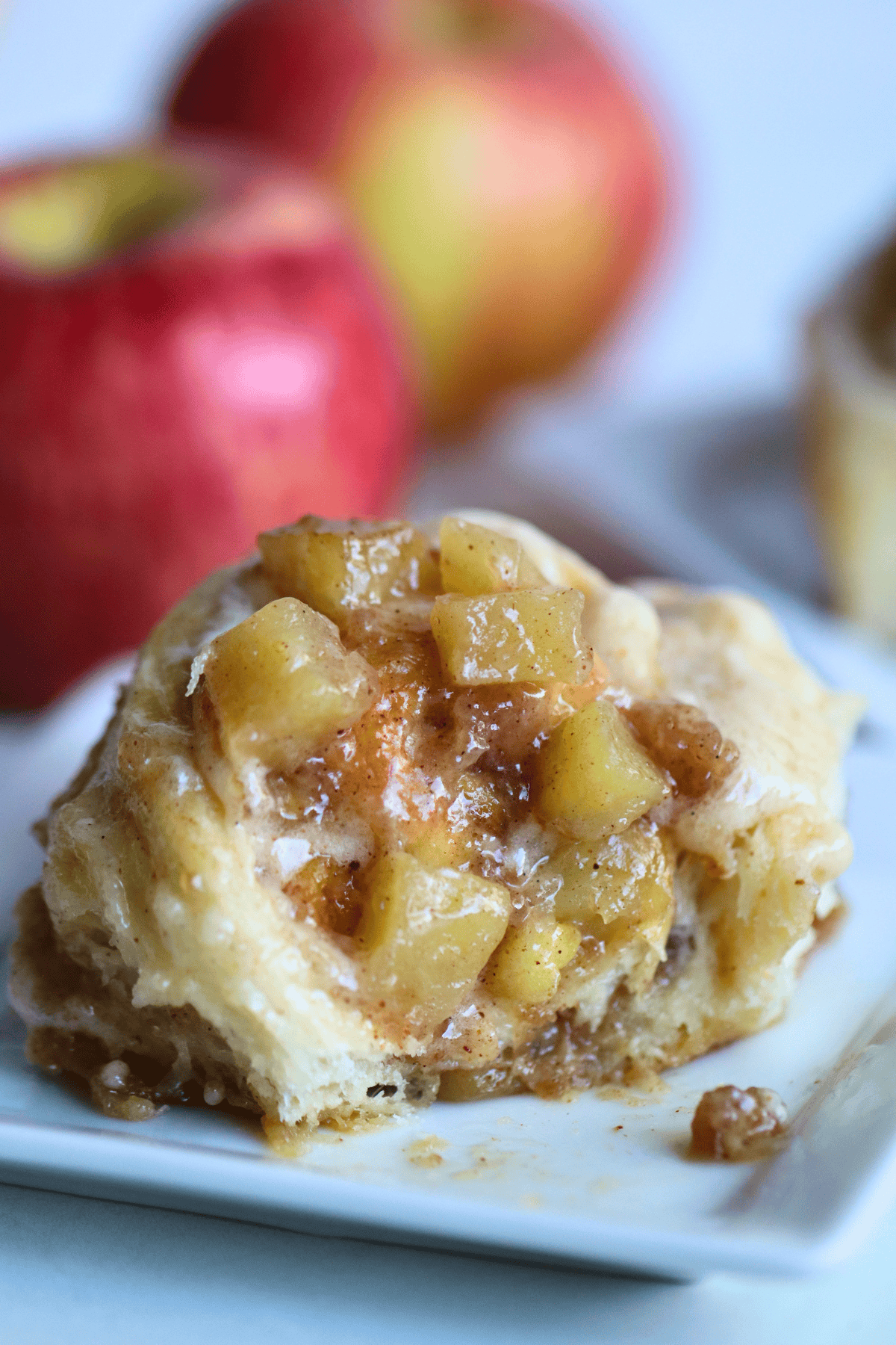 A fall inspired apple sourdough dessert on a white plate, with fresh apples in the background.