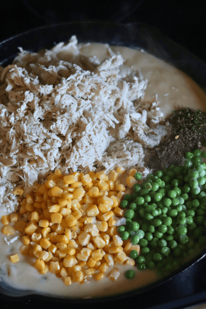 adding chicken, corn and peas to the pan