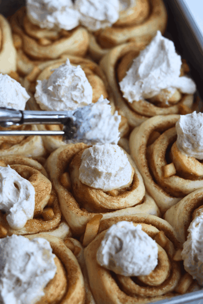 adding the frosting on top of sourdough discard apple cinnamon rolls